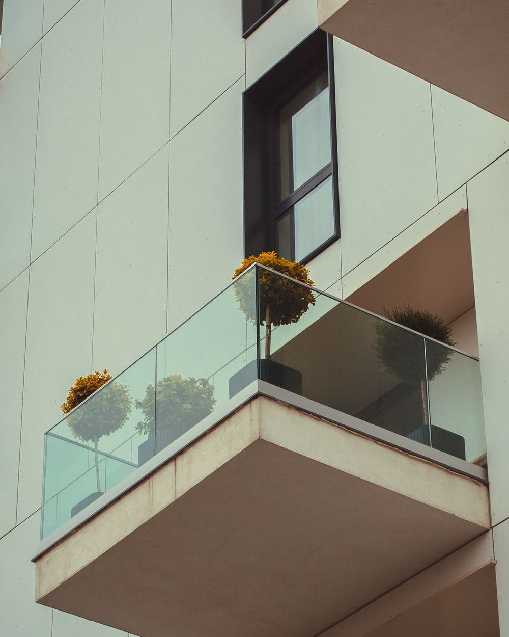 Fachada clara de edifício residencial com varandas de vidro